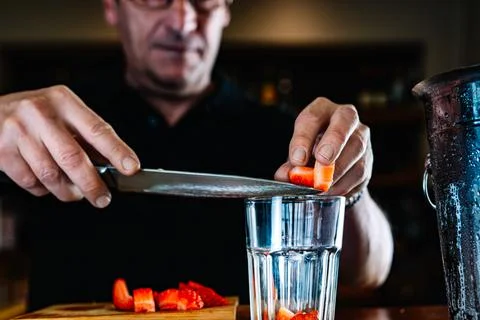 Hands of an experienced bartender pouring fruit into a glass cocktail glass Stock Photos