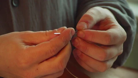 The hands of an experienced tailor thread a tailor's needle to make a bag made Stock Footage 143726110