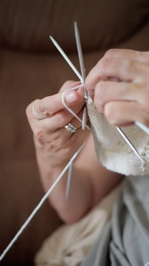 Hands expertly and skillfully knitting a beautiful, cozy white sock, showcasing Video stock 314775865