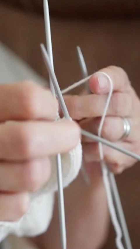 Hands expertly and skillfully knitting a beautiful, cozy white sock, showcasing Stock Footage 316635252