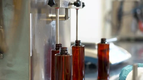 The hands of a factory worker place plastic bottles under an automated dispenser Stock Footage 311998819