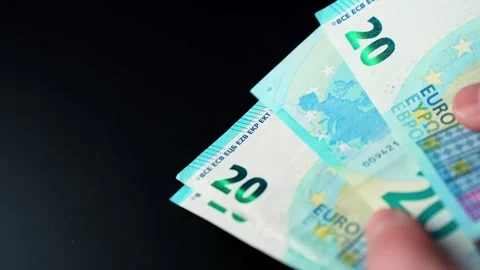 Hands fanning €20 banknotes on a black background with shallow focus. Perfect Stock Footage 328586374