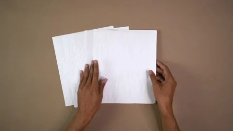 Hands fanning stack of white paper on brown background Stock Footage 344459063