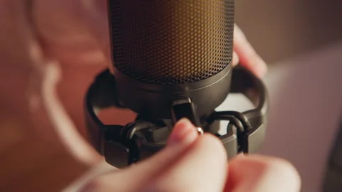 Hands fastening shock mount onto large studio microphone with colorful blue and Stock Footage 345660166