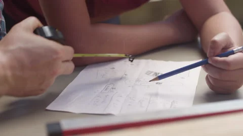Hands of a father and son going over plans and measurements for a home project Video stock 132528890