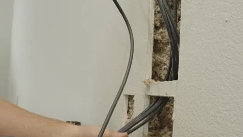 Hands feeding cables through an open wall 库存影片 348681359