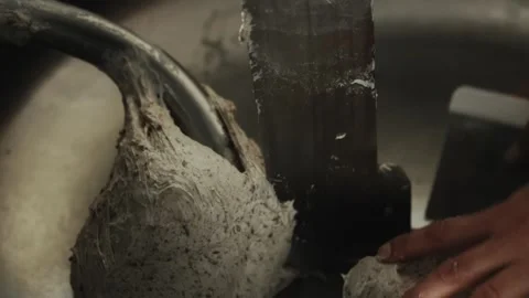 Hands of female baker scrape piece of fermented dough from side of industrial Stock Footage 339864891