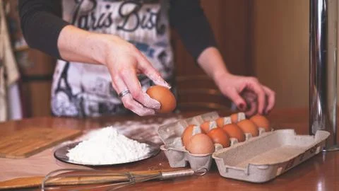 The hands of a female chef picking an egg for making dough while making bread Stock-Fotos