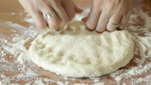 The hands of a female chef preparing a pizza dough base on a wooden table Stock Footage 315028659