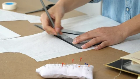 Hands of female tailor drawing pattern at paper in her studio Stock Footage 90378896