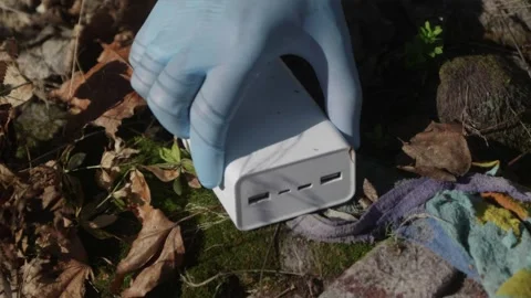 Hands finding discarded electronic power bank in forest moss Stock Footage 333118466