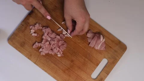 Hands finely dicing slices of ham with a kitchen knife on a wooden board, s.. Stock Footage 320954402