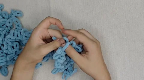 Hands finger knitting light blue plush loop yarn close up top view Stock-Footage 346305524