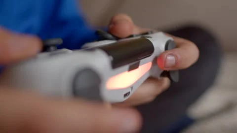 Hands firmly gripping a gaming controller, with a blurred background emphasizing Stock Footage 295932182