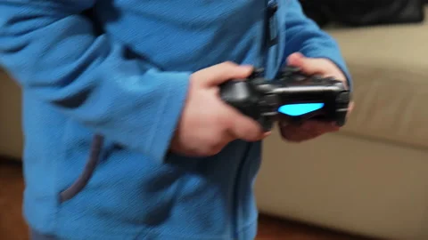 Hands of a five-year-old boy playing a game console with a joystick Видео 168310103