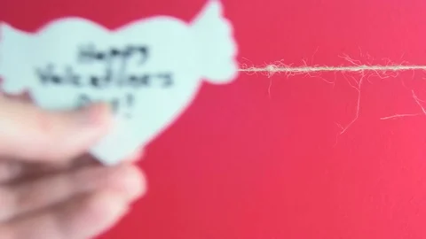 Hands fixing a white heart with congratulation and wings fixed with clothespin Stock Footage 73309721