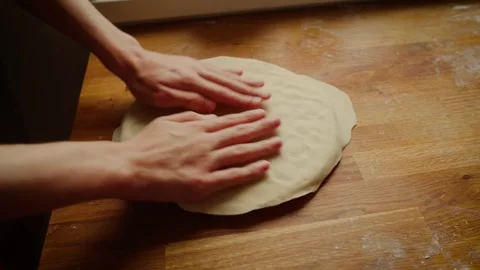 Hands flattening dough over dumpling mold on wooden surface. Fingers preparing Video stock 306373454