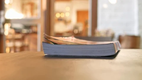 Hands flipping pages of a book placed on wooden table in the cafe. Stock Footage 122054272