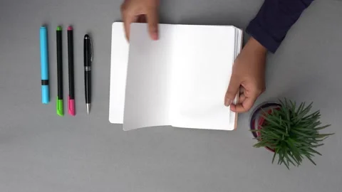 Hands flipping the pages of an empty notebook on a grey desk. Stock Footage 147405516