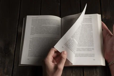 Hands flipping through pages of an open book Stock Photos