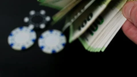 Hands flipping through a stack of 100 Euro bills, casino chips are on the table Stock Footage 262368701