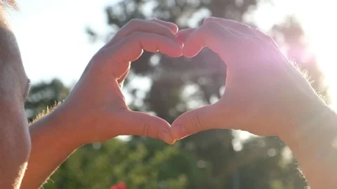 Hands fold heart. The rays of the sun shine through the heart at sunset. Symbol Stock Footage 135039733