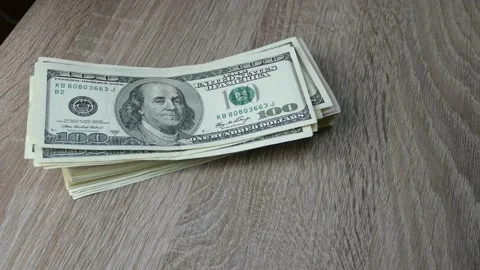 Hands fold many dollars in stack on wooden table. One banknote after another. Stock Footage 153626239