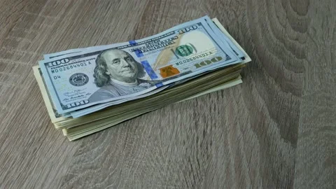 Hands fold many dollars in stack on wooden table. One banknote after another. Stock Footage 153626265