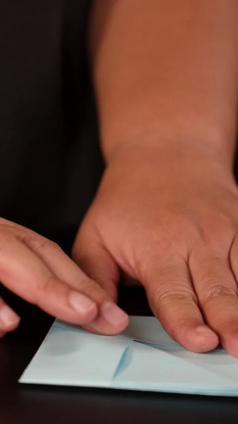 Hands Folding Blue Origami Paper on Dark Table Stock Footage 324889329
