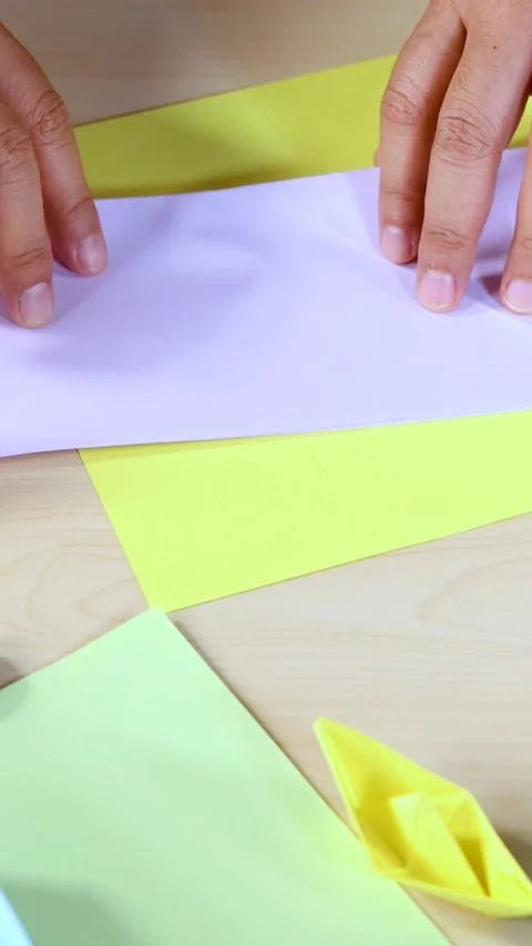 Hands Folding Colored Paper for Origami Boat Craft Tutorial Stock Footage 318569012