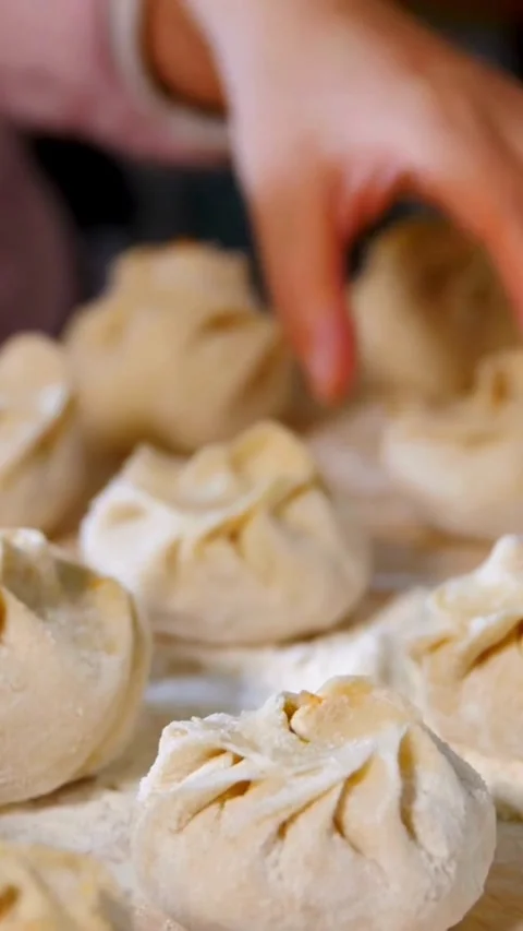 Hands folding dough to make dumplings on flour surface Stock Footage 331935656