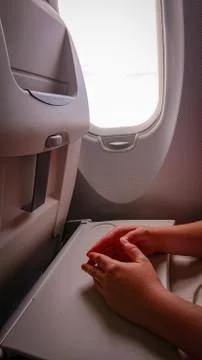 Hands on the folding table of the chair in the cabin of the aircraft near the Stock Photos