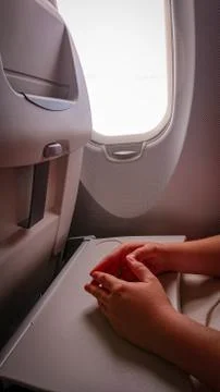 Hands on the folding table of the chair in the cabin of the aircraft near the Stock Photos