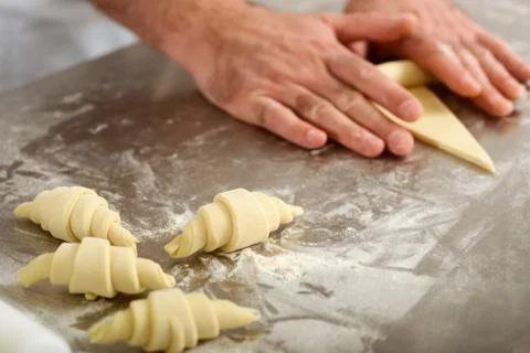 Hands forming crescent rolls. Making sweet and fluffy pastry Stock Photos