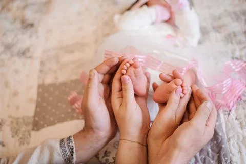 Hands forming a heart frame for the tiny feet of her newborn baby Stock Photos