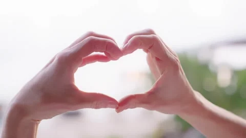 Hands forming heart shape against beach view with tropical plants and sea Stock Footage 303692574