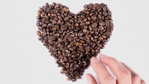 Hands forming heart shape out of coffee beans on clean grey background in slow Stock Footage 84148591