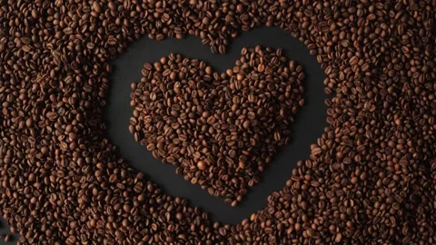 Hands forming a heart shape over coffee beans with heart shapes Stock Footage 338441354