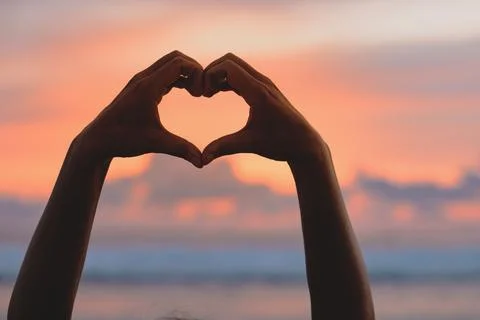 Hands forming a heart shape with sunset silhouette Stock Photos
