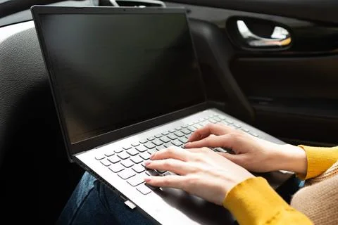 Hands in the frame typing text on a laptop while sitting in a car, freelancer Stock Photos