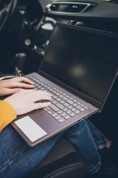 Hands in the frame typing text on a laptop while sitting in a car, freelancer Stock Photos