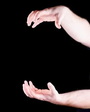 Hands Framing an Invisible Object Against a Black Background Stock Photos