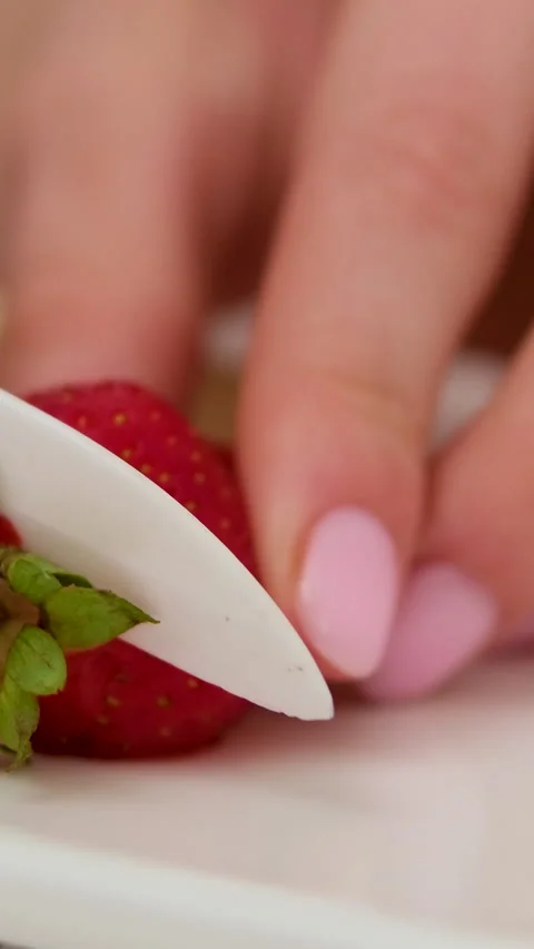 Hands, fruit and diet with a knife in the hand of a woman cutting a strawberry Stock Footage 277524210