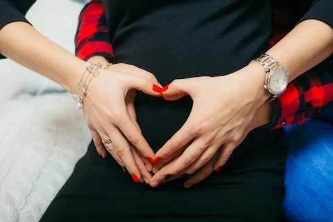 Hands of future parents are making the shape of heart on the tummy of the Foto stock
