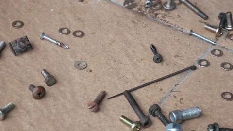 Hands Gathering Mixed Screws, Bolts and Nuts Across Floor Surface Stock Footage 336755743