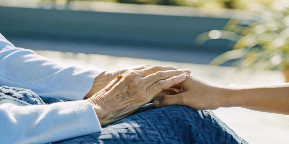 Hands gently holding an elderly person's hand with the concept of love and care Stock Photos