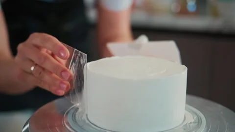 Hands gently peel plastic wrap from a frosted cake 스톡 동영상 336098050