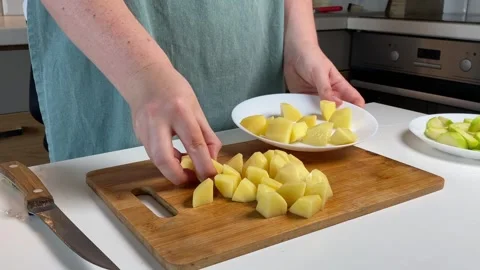 Hands gently place raw potato cubes on white plate, cooking moment filled w.. Stock Footage 320955651