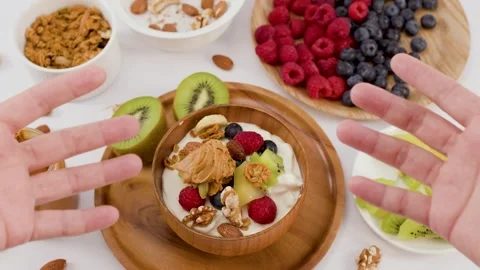 Hands Gesturing Over Healthy Yogurt Bowl with Fresh Fruit and Nuts Stock Footage 338051755
