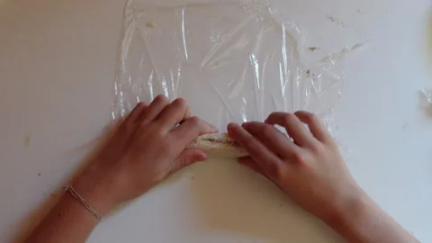Hands of a girl rolling of filled bread with cling film Stock Footage 285949813